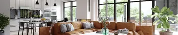 Open concept kitchen and living room remodel with white cabinets, brown leather sofa, black window frames, and modern pendant lights