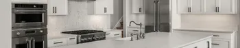 White kitchen remodel with custom cabinets, stainless steel refrigerator, wall oven, gas cooktop, and bright marble-style counters