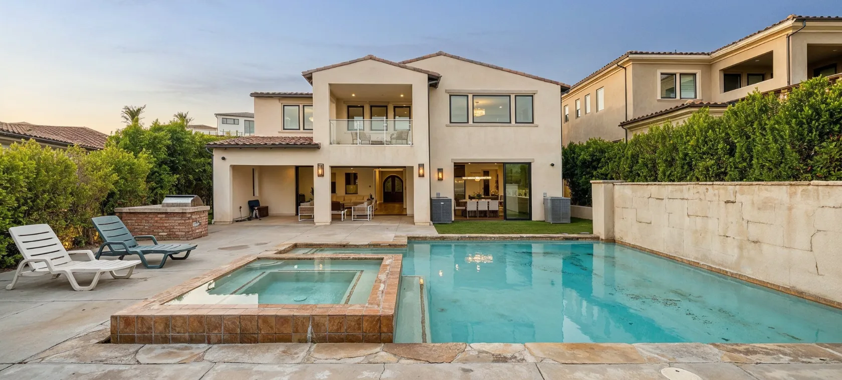 Before backyard remodeling project in Los Angeles showing an older pool and spa area with dated tile, plain concrete patio, lounge chairs, and backyard space ready for outdoor living upgrades