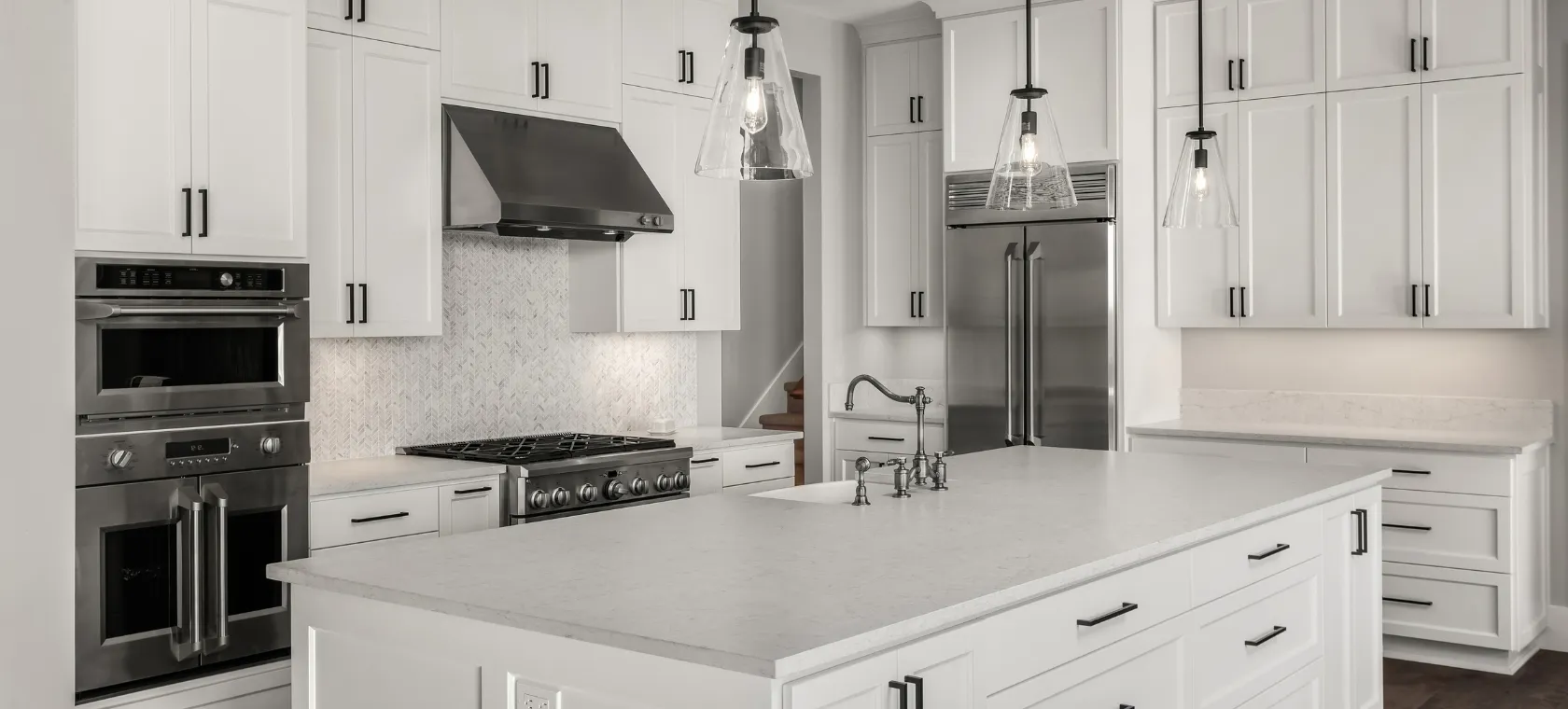 After kitchen remodeling project in Los Angeles featuring white shaker cabinets, marble style island, stainless steel appliances, pendant lighting, modern backsplash, and bright luxury kitchen design