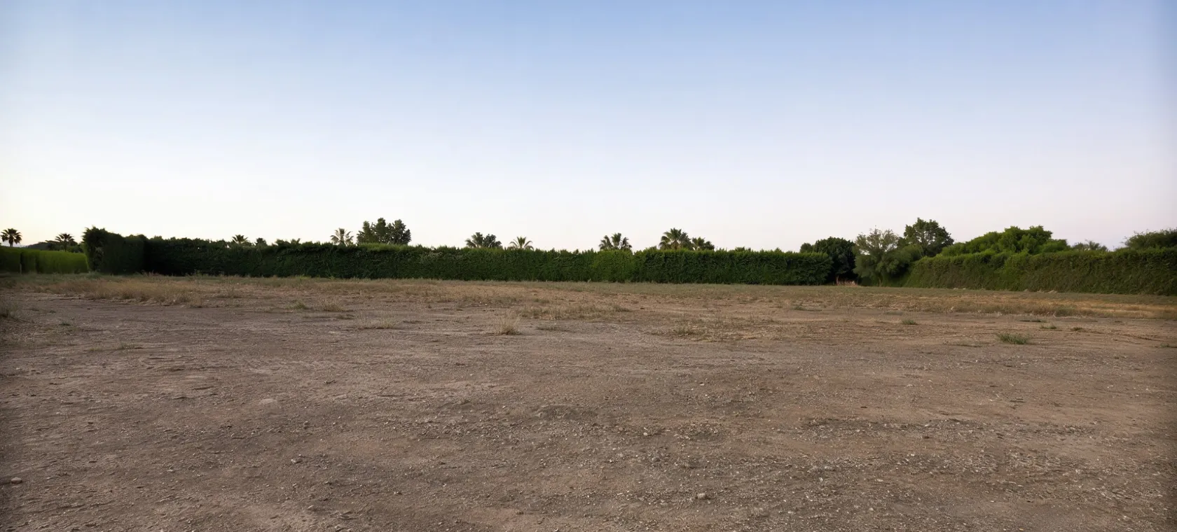 Before new construction project in Los Angeles showing an empty dirt lot with open land, surrounding hedges, and cleared space ready for ground up custom home construction