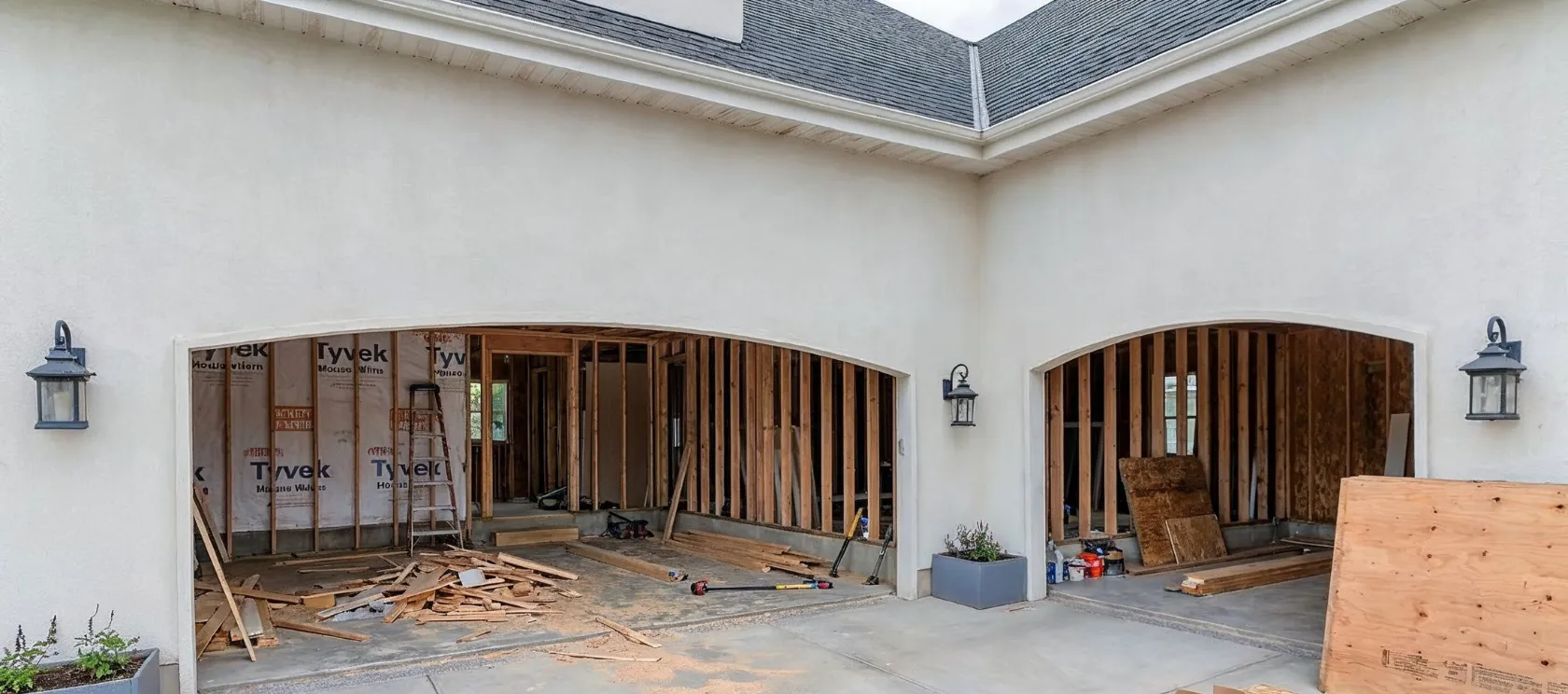 Garage conversion ADU in Los Angeles with open garage bays, exposed wood framing, construction materials, and space being prepared for livable ADU use
