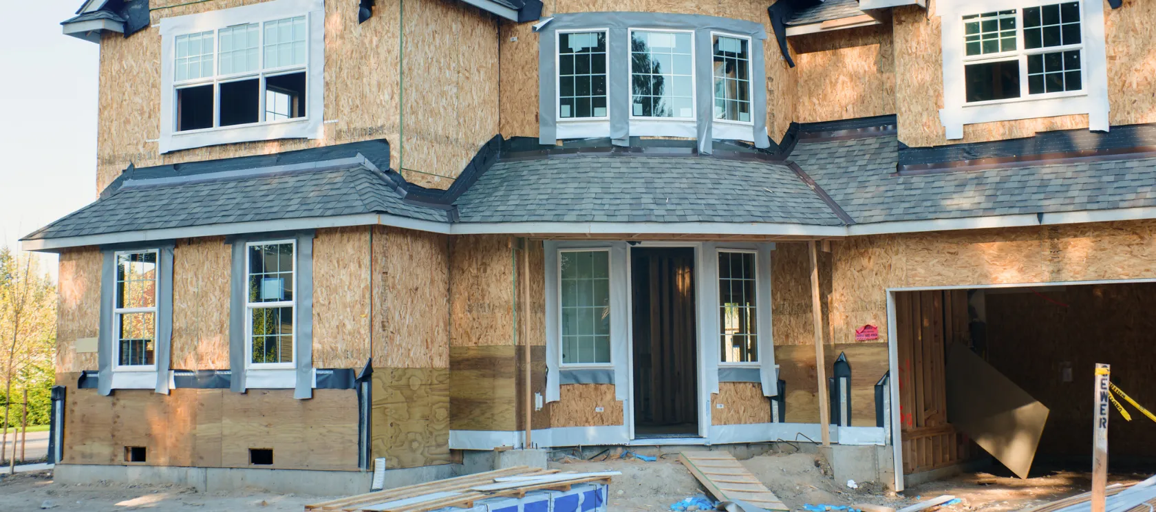 New construction in Los Angeles showing custom home framing, exterior plywood sheathing, roof installation, windows, and residential building progress