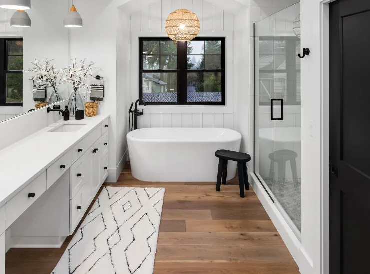 Bathroom remodeling in Los Angeles with a freestanding tub, glass shower enclosure, double vanity, modern black fixtures, and warm wood flooring