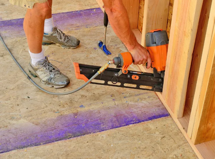 General contractor in Los Angeles performing framing and carpentry work with a pneumatic nail gun during residential construction and structural floor installation