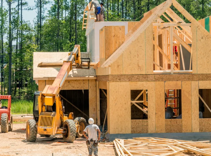 New construction in Los Angeles showing custom home framing, active jobsite equipment, workers on site, and wood structural assembly in progress